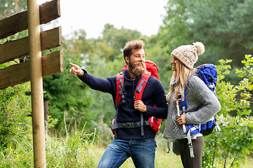 Image showing couple of travelers with backpacks at signpost