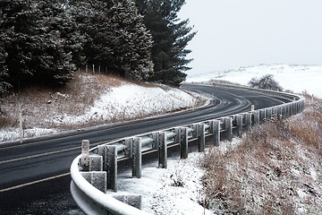 Image showing Curving road through snow covered hills