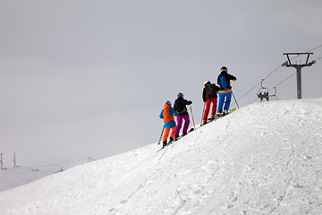 Image showing Skiers before downhill on off-piste slope and overcast misty sky