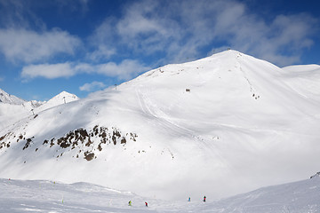 Image showing Skiers and snowboarders downhill on trace and mountains with clo