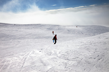 Image showing Skiers and snowboarders downhill on snow slope