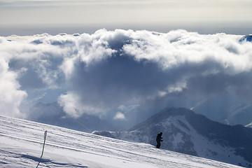 Image showing Skier downhill on ski slope and sunlight storm clouds