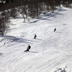 Image showing Skier and snowboarders on ski slope at sun winter day