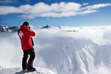 Image showing Rescuer at top of mount and snow mountains in fog