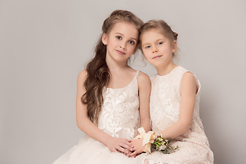 Image showing Little pretty girls with flowers dressed in wedding dresses