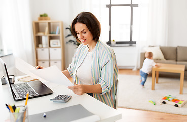 Image showing mother working with papers and baby boy at home