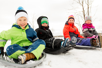 Image showing happy little kids sliding on sleds in winter