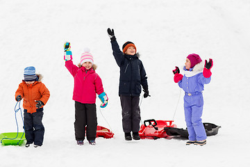 Image showing happy kids with sleds waving hands in winter