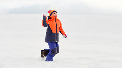 Image showing happy girl playing and throwing snowball in winter