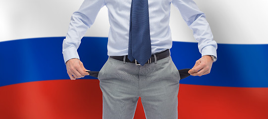 Image showing businessman with empty pockets over flag of russia