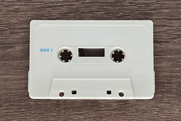 Image showing Vintage white audio cassette tape on brown wooden background. Side 1