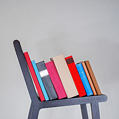 Image showing Stack of colorful books on black wooden chair.