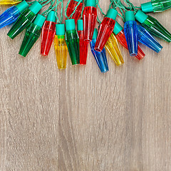 Image showing Christmas colorful lights on brown wooden background.