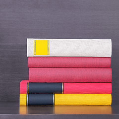 Image showing stack of new colorful books in the wooden bookself.