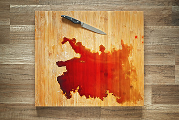 Image showing Blood and knife on the big wooden cutting board.