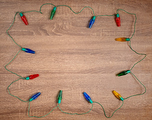 Image showing Christmas colorful lights on brown wooden background.