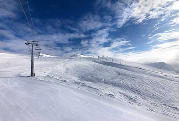 Image showing Ski slope, chair-lift on ski resort and blue sky with sunlight c