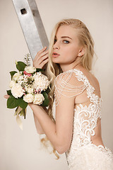 Image showing Bride in beautiful dress standing indoors in white studio interior like at home. Trendy wedding style shot. Young attractive caucasian model like a bride tender looking.