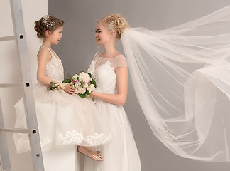 Image showing Little pretty girls with flowers dressed in wedding dresses