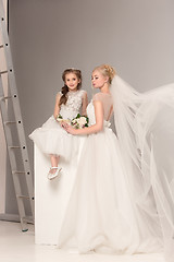 Image showing Little pretty girls with flowers dressed in wedding dresses