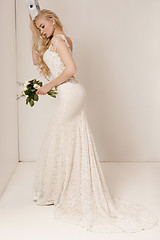 Image showing Bride in beautiful dress standing indoors in white studio interior like at home. Trendy wedding style shot. Young attractive caucasian model like a bride tender looking.