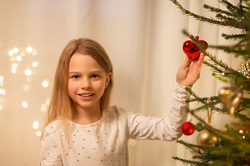 Image showing happy girl in red dress decorating christmas tree