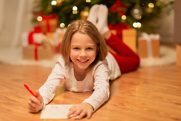 Image showing smiling girl writing christmas wish list at home