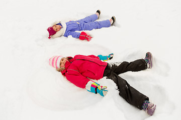 Image showing happy little girls making snow angels in winter