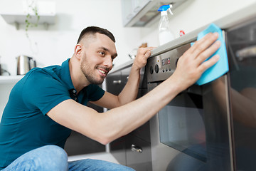 Image showing man with rag cleaning oven door at home kitchen