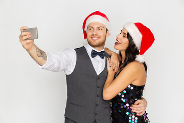 Image showing couple in santa hats aking selfie at christmas