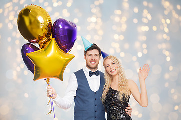 Image showing happy couple in party hats with balloons