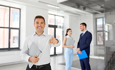 Image showing realtor with folder pointing at you at office