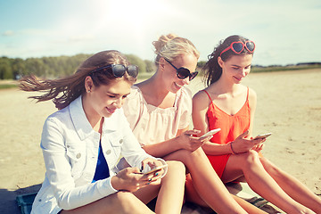 Image showing group of happy women with smartphones on beach