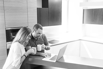 Image showing couple drinking coffee and using laptop at home