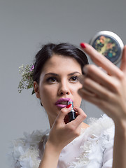 Image showing bride paints lips with lipstick