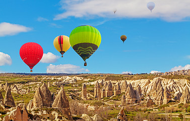 Image showing Hot air baloons flying over spectacular stone cliffs in Cappadocia