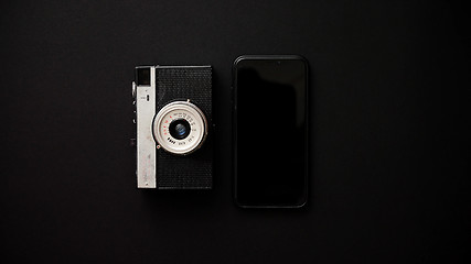 Image showing Old retro film camera and modern smartphone on black background