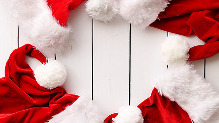 Image showing Santa Claus hats on white wooden desk with blank copy space.