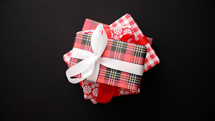 Image showing Red gift box with red bow on black table, top view