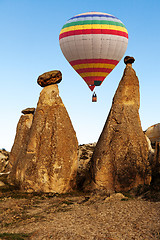 Image showing Hot air baloon flying over spectacular stone cliffs in Cappadocia