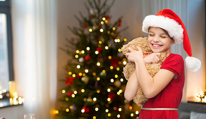 Image showing girl in santa hat with teddy bear on christmas