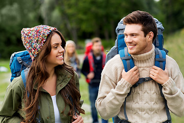 Image showing happy friends or travelers with backpacks hiking