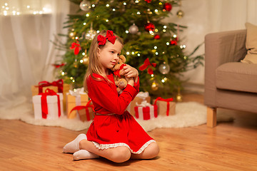 Image showing girl in red dress hugging teddy bear at home