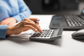 Image showing businesswoman with calculator at night office