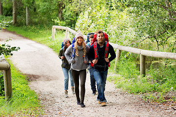 Image showing happy friends or travelers hiking with backpacks