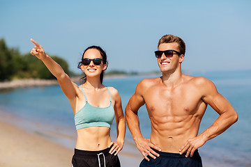 Image showing happy couple in sports clothes and shades on beach