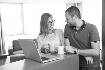 Image showing couple drinking coffee and using laptop at home