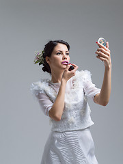 Image showing bride paints lips with lipstick