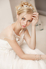 Image showing Bride in beautiful dress standing indoors in white studio interior like at home. Trendy wedding style shot. Young attractive caucasian model like a bride tender looking.