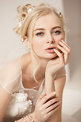 Image showing Bride in beautiful dress standing indoors in white studio interior like at home. Trendy wedding style shot. Young attractive caucasian model like a bride tender looking.